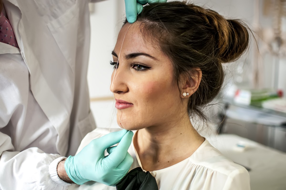Woman having facial skin checked by doctor