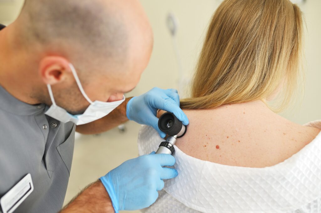 Dermatologist examining mole on woman's back