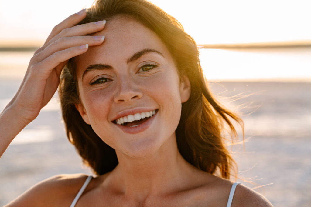 Woman smiling with hand in hair outdoors