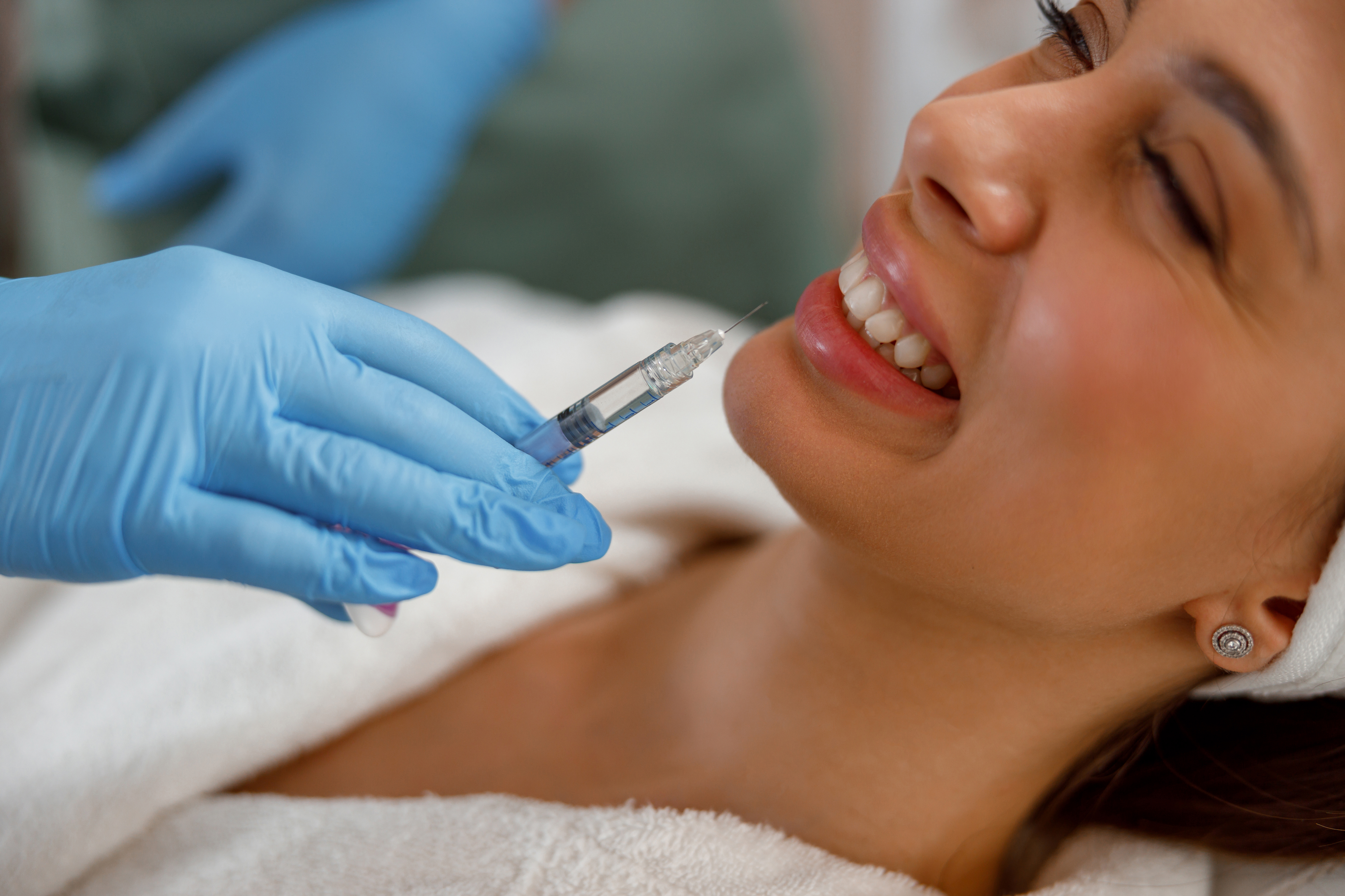 Woman smiling receiving lip filler injection